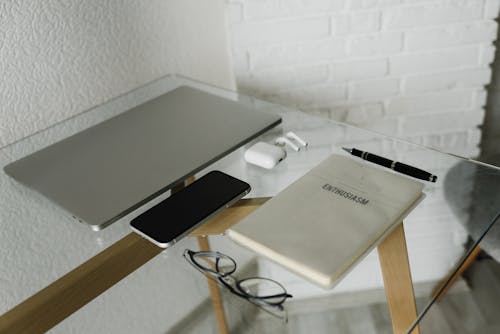 Free Wireless Devices on Glass Desk with Notebook and Pen Stock Photo