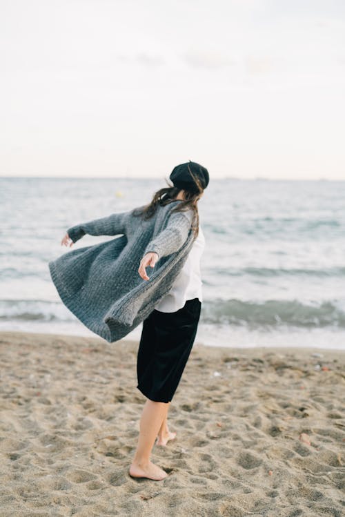 Wanita Dengan Jaket Putih Dan Rok Hitam Berdiri Di Tepi Pantai