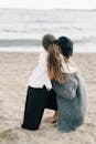 Woman in White Long Sleeve Shirt and Black Pants Standing on Beach