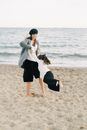 Woman in Black Skirt and White Cardigan Standing on Beach