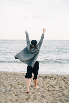 一名妇女在海边举起双臂，享受和平的背影，拥抱自由与安宁