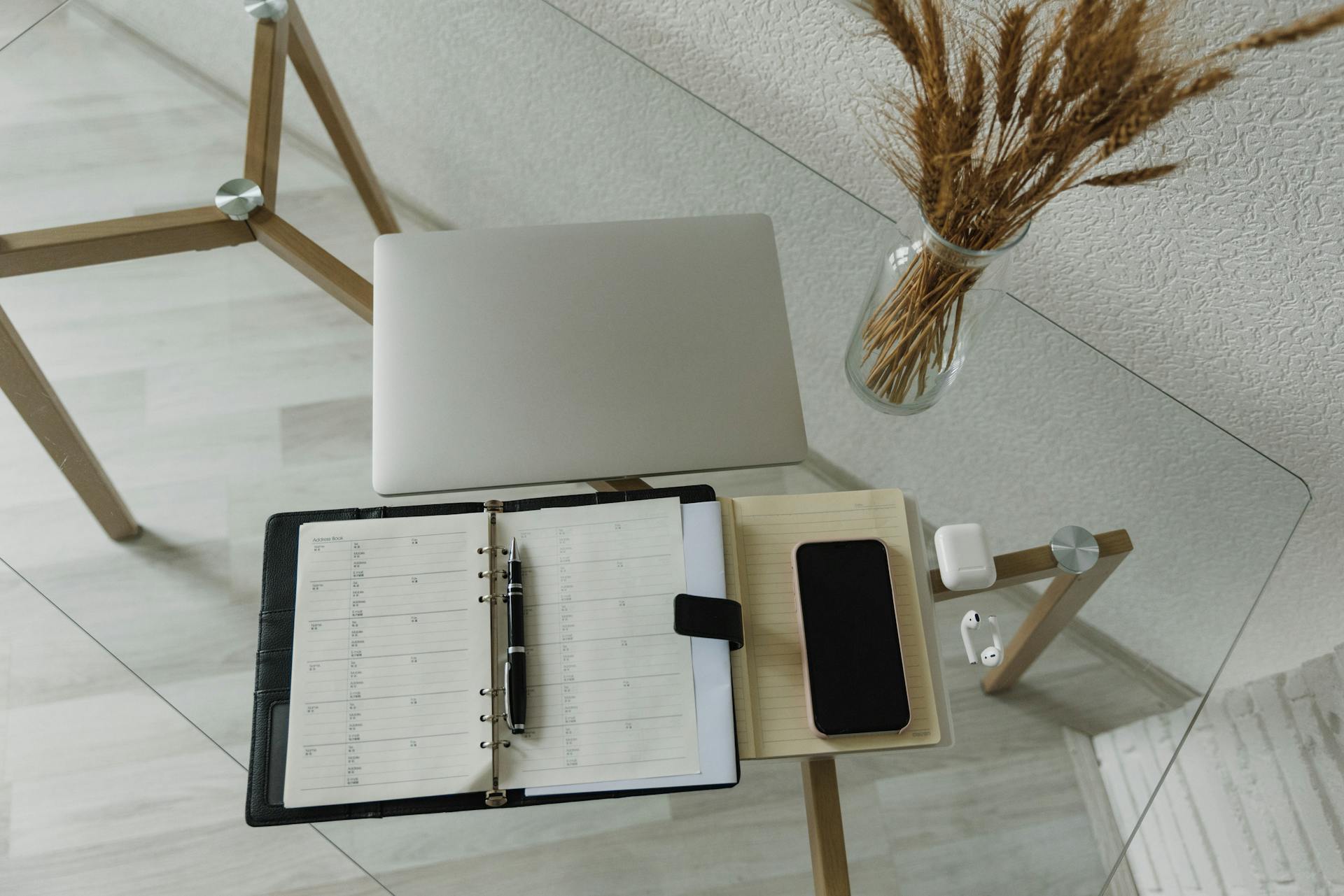 An Organizer and Pen Beside a Notebook on a Glass Desk with Wireless Gadgets