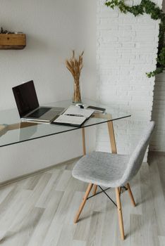 Stylish home office setting with a glass desk, laptop, and minimal decor.