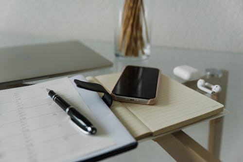Free Smartphone and Black Pen on an Open Notebook Stock Photo