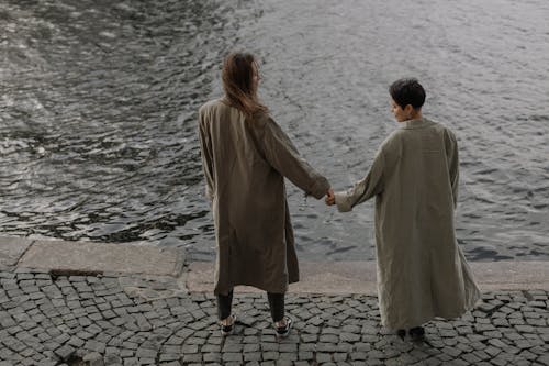 Free A Couple Holding Hands by a Riverside Stock Photo