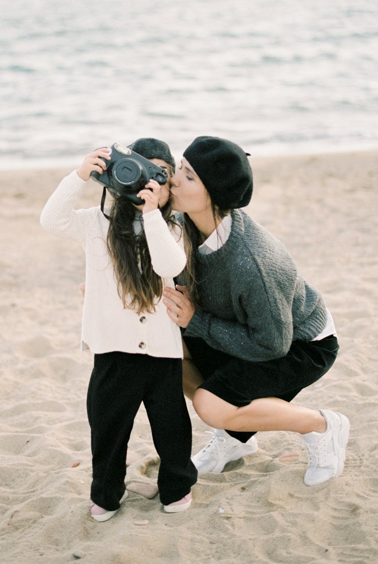 Mother Kissing Her Child On The Beach