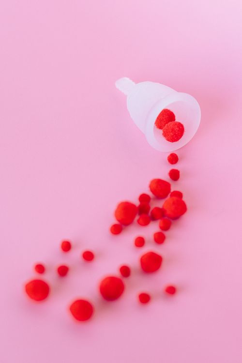 Free White menstrual cup with red elements on pink, promoting sustainable period products. Stock Photo