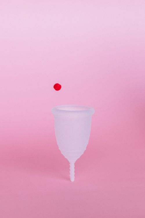 Free A white menstrual cup with a red droplet on pink background symbolizing menstrual health. Stock Photo