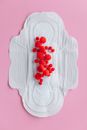 在粉红色背景的月经垫上，乌藨子以艺术形式呈现，象征着月经