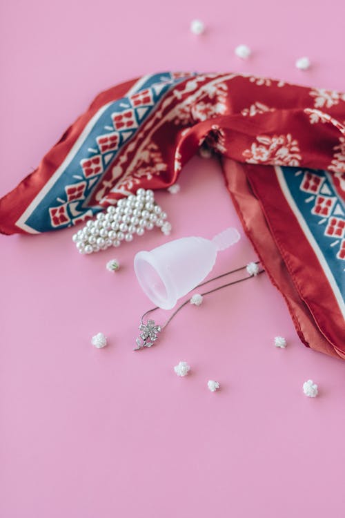 Copo menstrual rosa de silicone com rosa sobre fundo branco, conceito de  menstruação