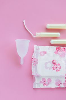 粉红色背景上，月经杯、护垫和卫生棉条的顶视图
