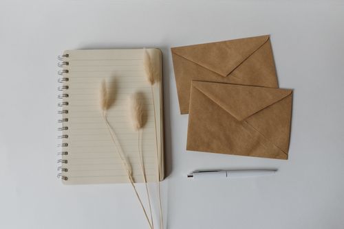 Free Flat lay image featuring a notebook, brown envelopes, and a pen on a white background. Perfect for mockups. Stock Photo