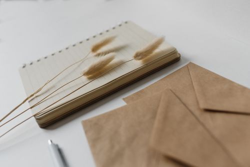 Free Elegant workspace setup with bunny tail grass, notebook, and envelopes for a serene and creative environment. Stock Photo