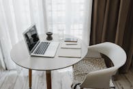 时尚的家庭办公室里，圆桌上摆放着笔记本电脑和智能手机