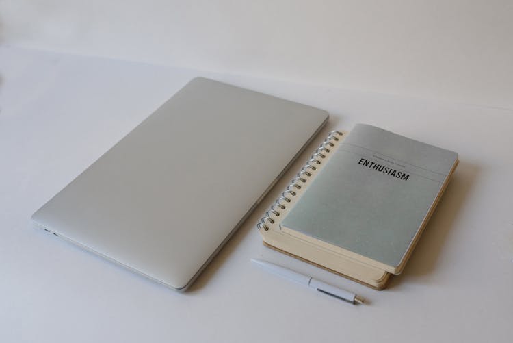 A Laptop Beside Notebooks