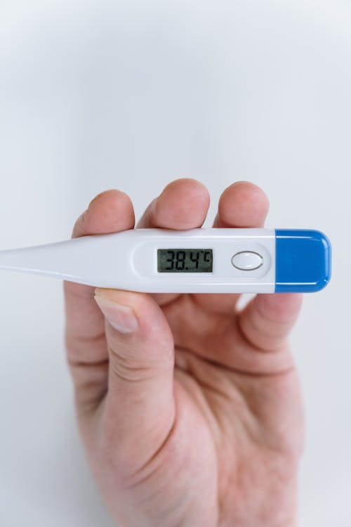 Person Holding White and Blue Thermometer at 38 4