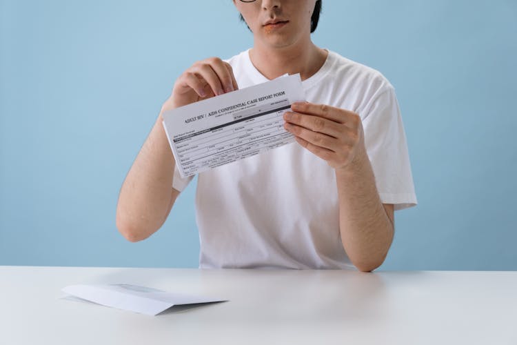 Man In White T-shirt Holding HIV/AIDS Paper Form