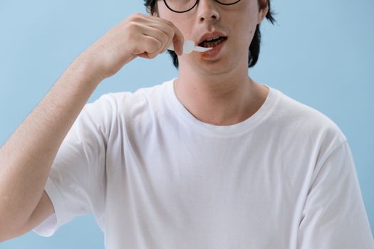 特写镜头中，一个人在蓝色背景下使用点滴器服药