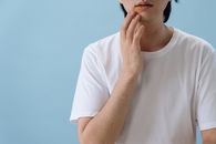 一名男子触摸自己脸部的特写，显示出皮肤病或过敏的迹象