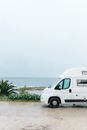 海边停着一辆白色货车，景色优美，非常适合旅行和冒险爱好者