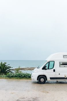 海边停着一辆白色货车，景色优美，非常适合旅行和冒险爱好者
