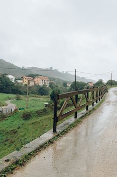 雨天时，可以看到乡村土路旁带有木栅栏和房屋的风景