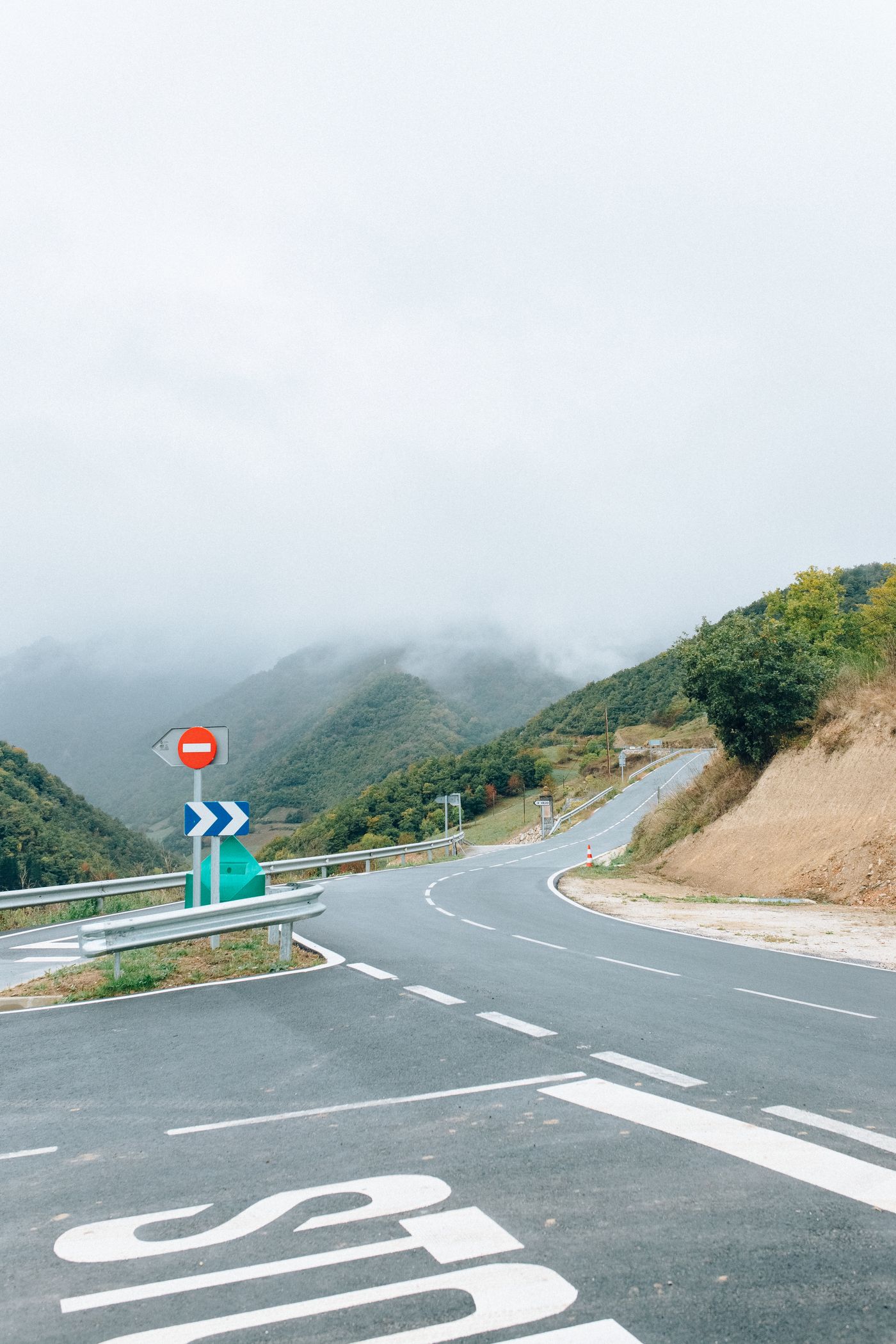 A crossroads on a road through misty hills