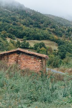 一座古色古香的砖砌小屋，静静地坐落在青山叠翠、云雾缭绕的群山之中