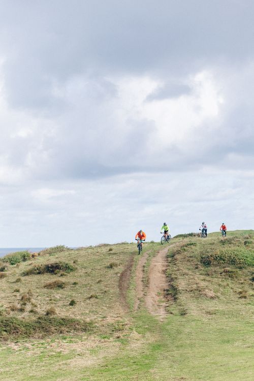 Free Cyclists enjoying an outdoor ride on a scenic dirt path under a cloudy sky. Stock Photo