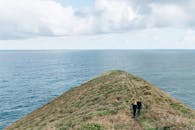 一对夫妇在俯瞰大海的草地悬崖小径上享受风景优美的徒步旅行