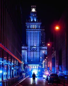 华沙的文化与科学宫在夜间被剪影人物和路灯照亮