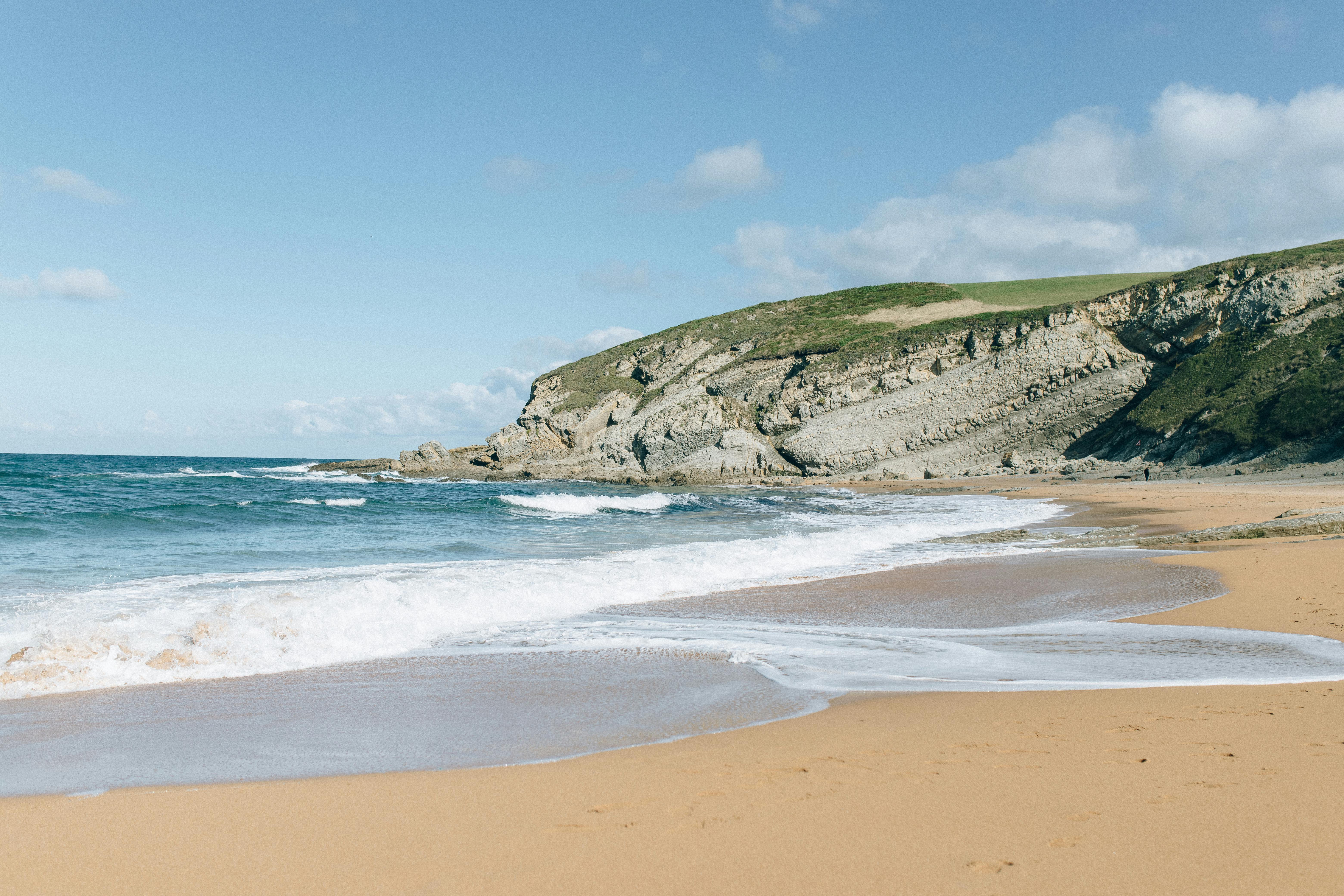 brown sand beach near green mountain under blue sky