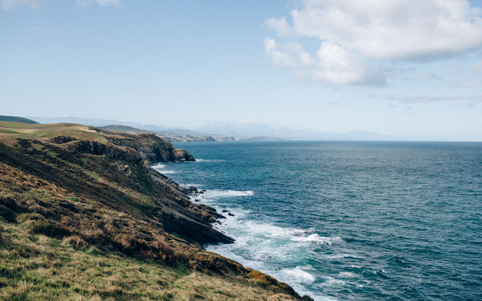Scenic coastal cliffs with ocean waves under a clear blue sky