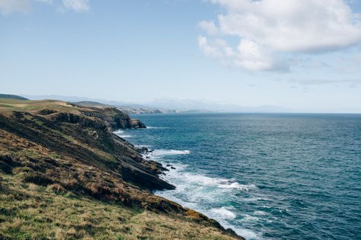 清澈的蓝天下，海浪在风景优美的沿海悬崖边翻滚，描绘出自然美景