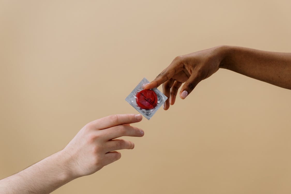 A person passing a red condom to another person. 
