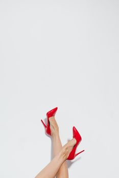 Stylish red high heels worn by a woman against a white background, featuring copy space.