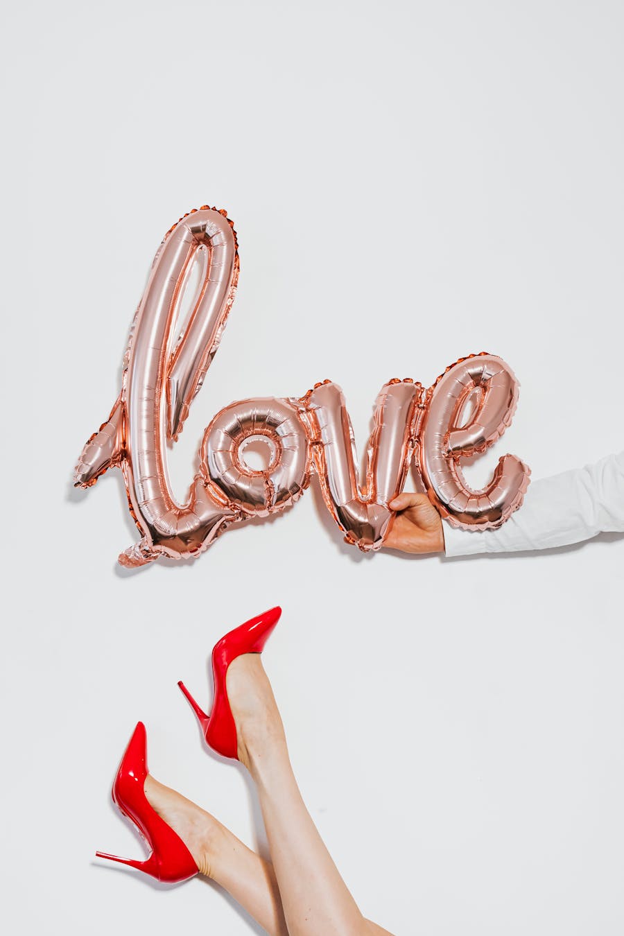 Elegant display of love with rose gold balloon and striking red heels. Perfect for Valentine's themes.