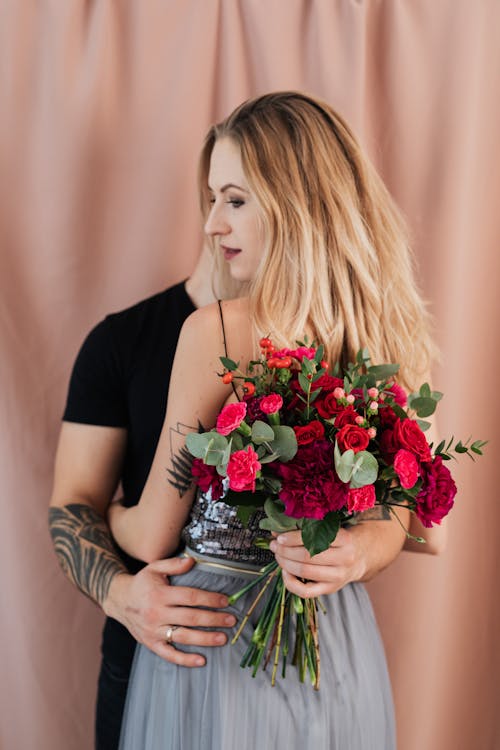 Couple Embracing and Bouquet Behind Woman