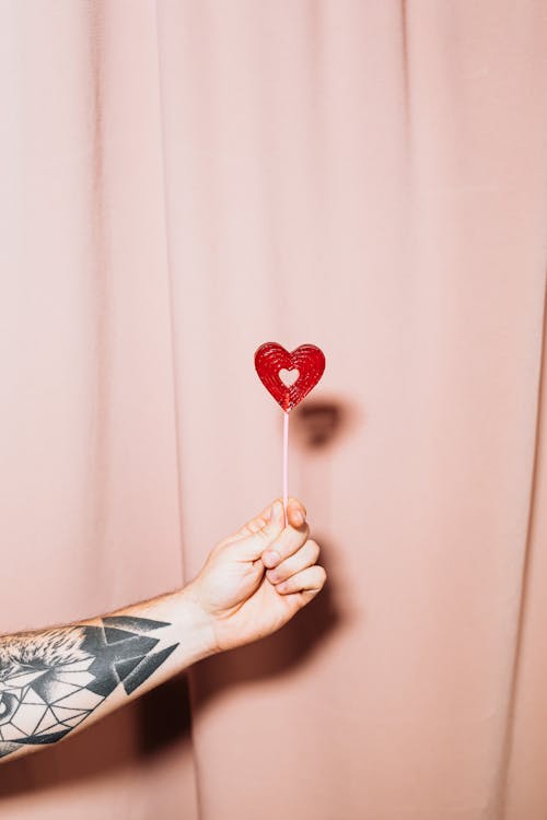 Person Holding Red Heart Lollipop