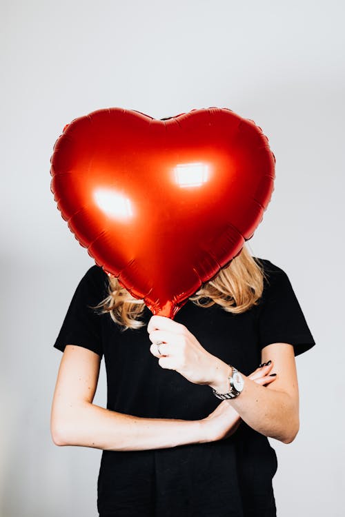 Woman in Black Shirt Holding Heart Balloon