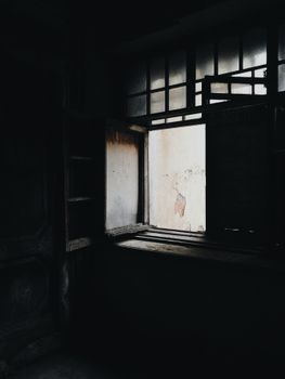 废弃房间光线昏暗，窗户开着，投射出怪异的阴影