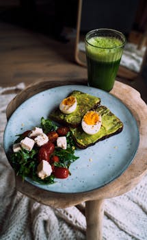 Delicious avocado toast with eggs and a refreshing green smoothie on a wooden table.