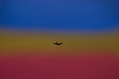 Free Silhouette of airplane landing gear transporting people or goods soaring over bright colorful sky Stock Photo