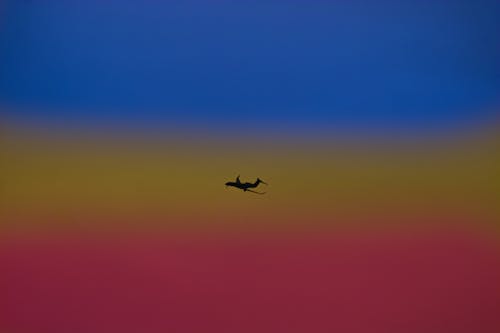 Silhouette of airplane landing gear transporting people or goods soaring over bright colorful sky