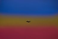 Silhouette of airplane landing gear transporting people or goods soaring over bright colorful sky