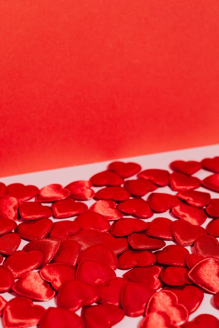 Close-up of red heart-shaped patches on a vibrant pink background, perfect for Valentine's décor.