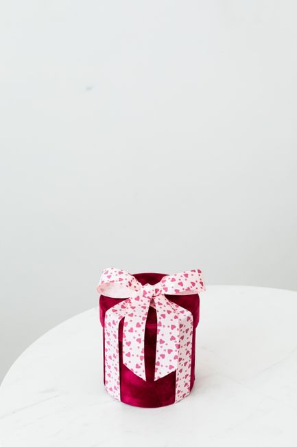A beautifully wrapped gift box with a heart-patterned bow on a white background, perfect for special occasions.