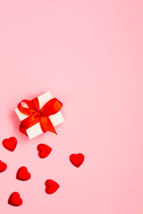 Free Valentine's Day gift with red hearts on a pink background, perfect for romantic occasions. Stock Photo