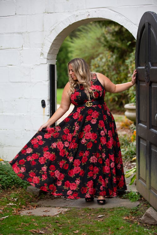 Elegant positive woman in bright stylish dress near door