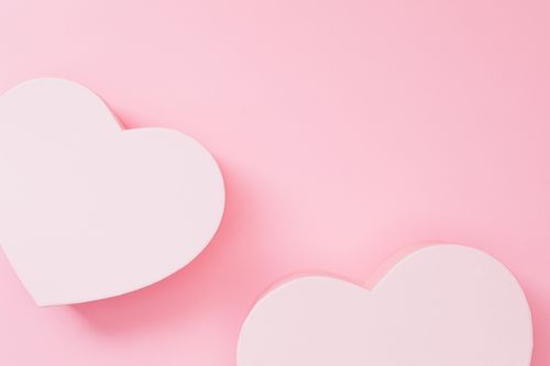 Free Two minimalist white heart shapes on a pastel pink background, perfect for designs related to love and romance. Stock Photo